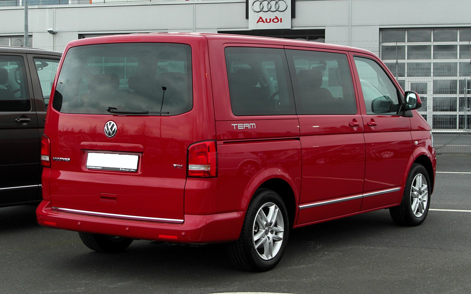 Rear and side view of red multi-purpose van with alloy wheels.