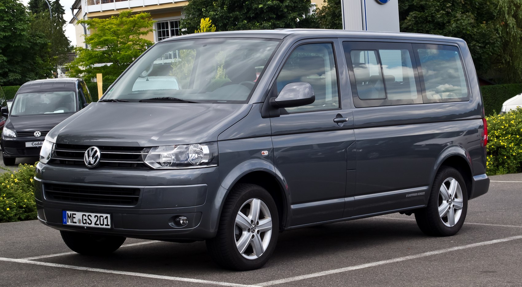 Front side view of gray minivan with alloy wheels and large windows