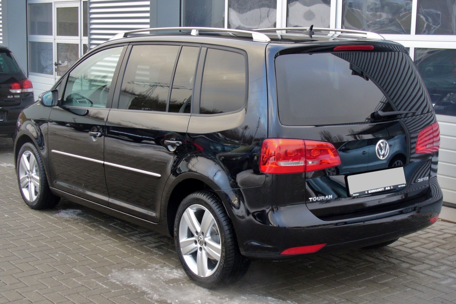 Rear and side view of a black MPV with roof rails and distinct tail lights