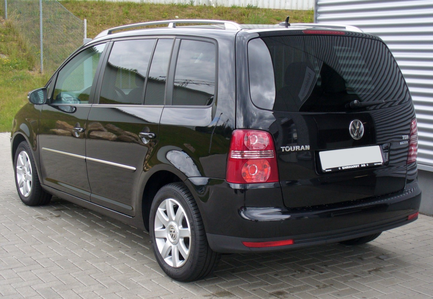 Rear-side view of MPV with tinted windows and roof rails