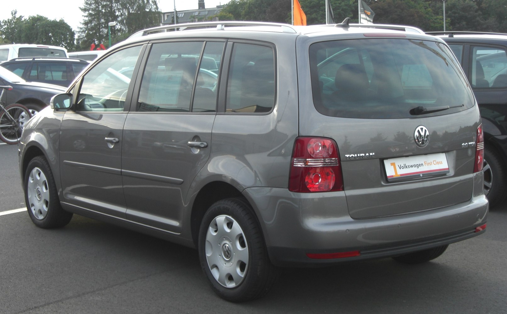 Rear and side view of a silver MPV with distinct tail lights and roof rails