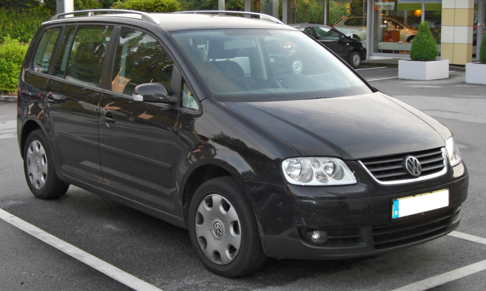Front side view of black MPV with roof rails and distinctive headlights