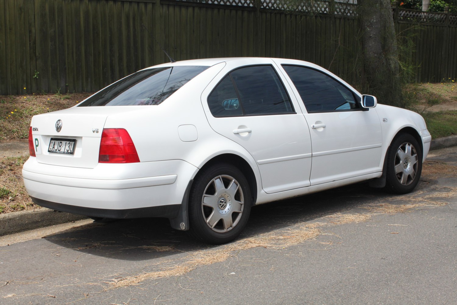 White sedan rear side with alloy wheels and rear spoiler