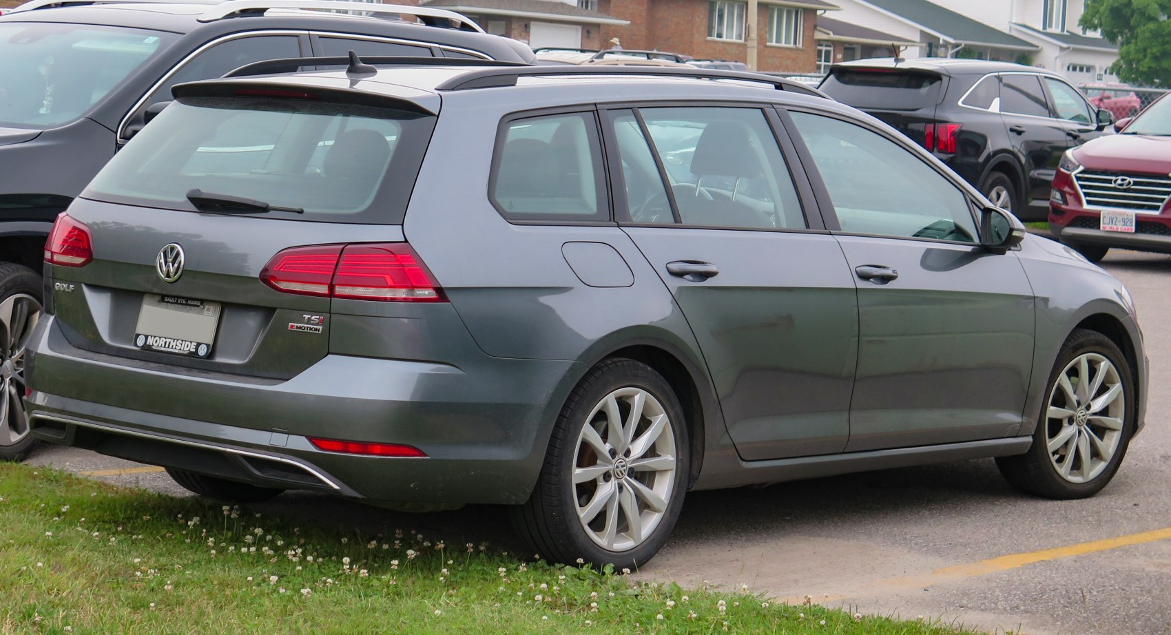 Rear-side view of a grey station wagon with alloy wheels and roof rails