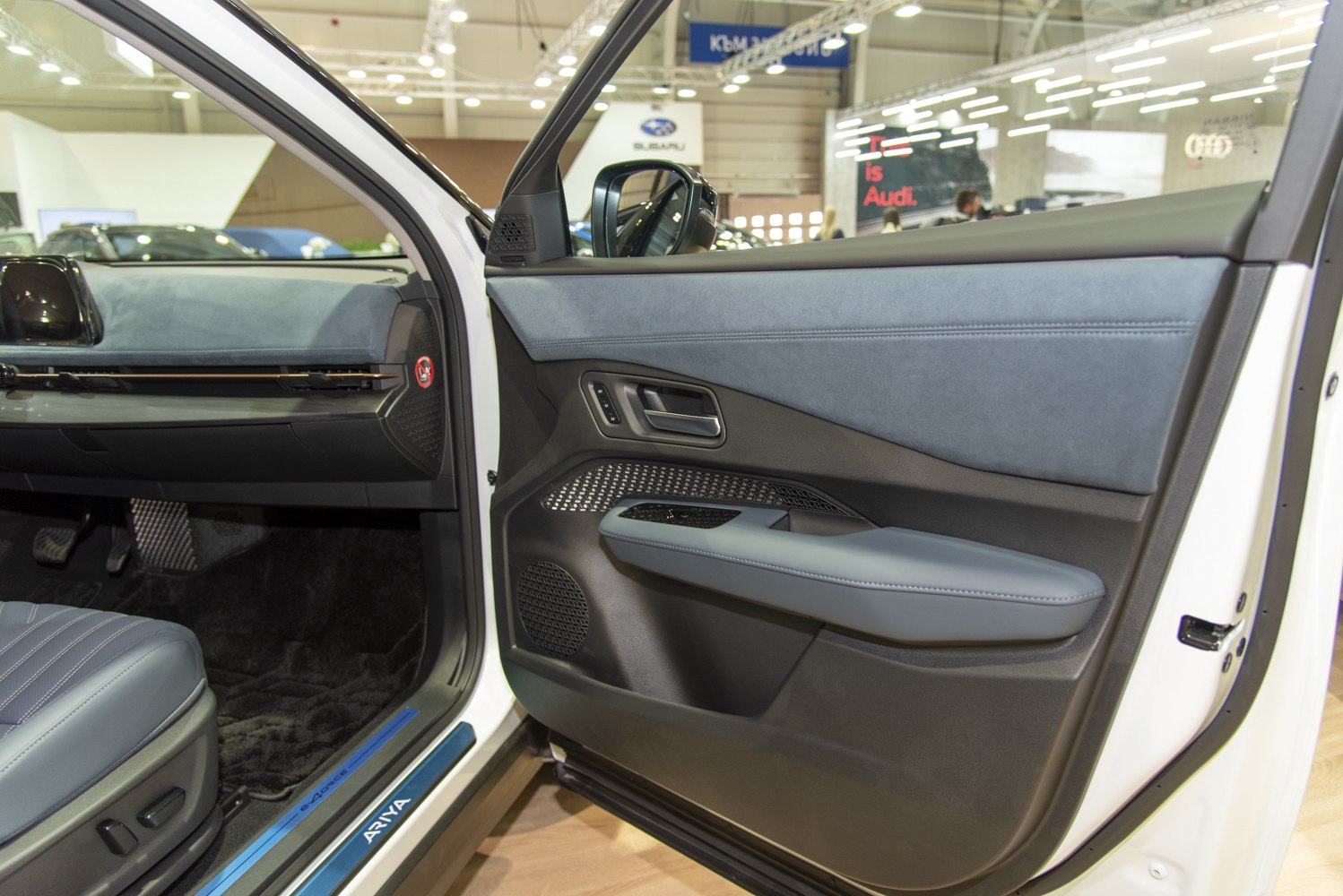 Modern interior door panel with blue upholstery and speaker grill.