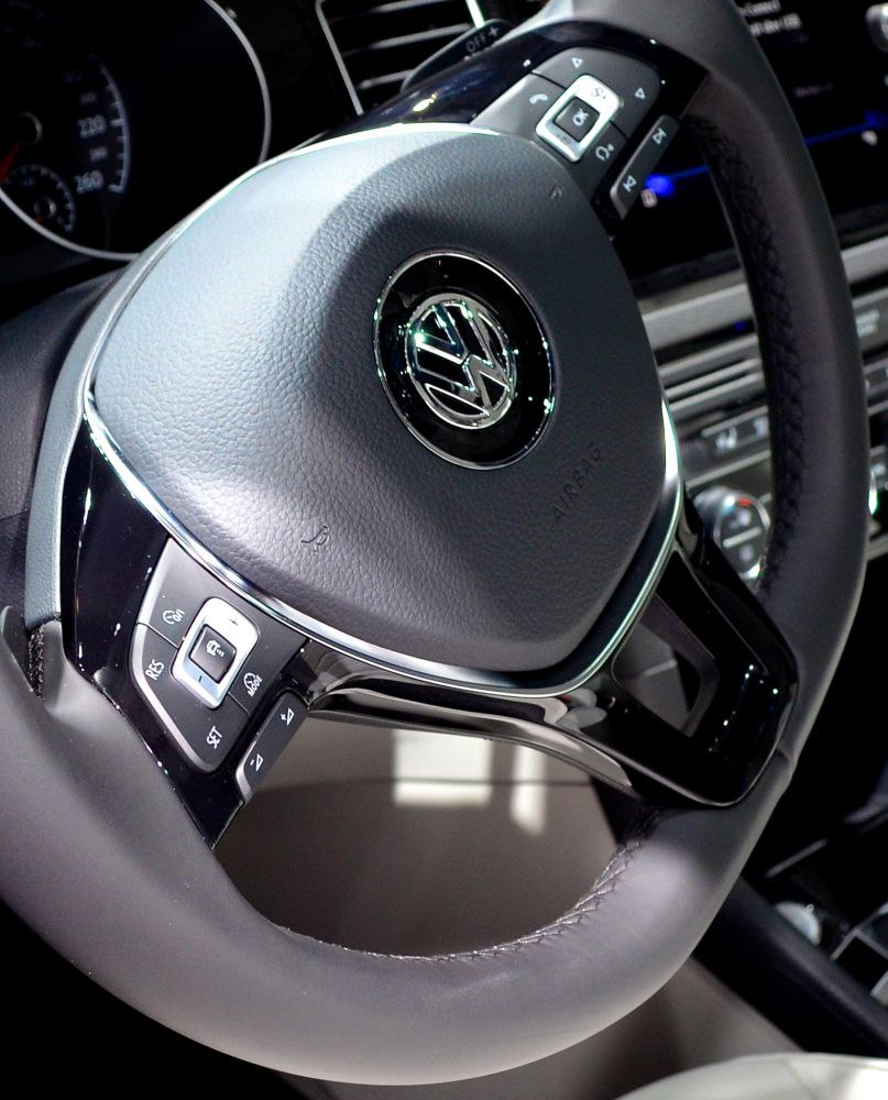 Close-up of a steering wheel with control buttons and leather wrap.