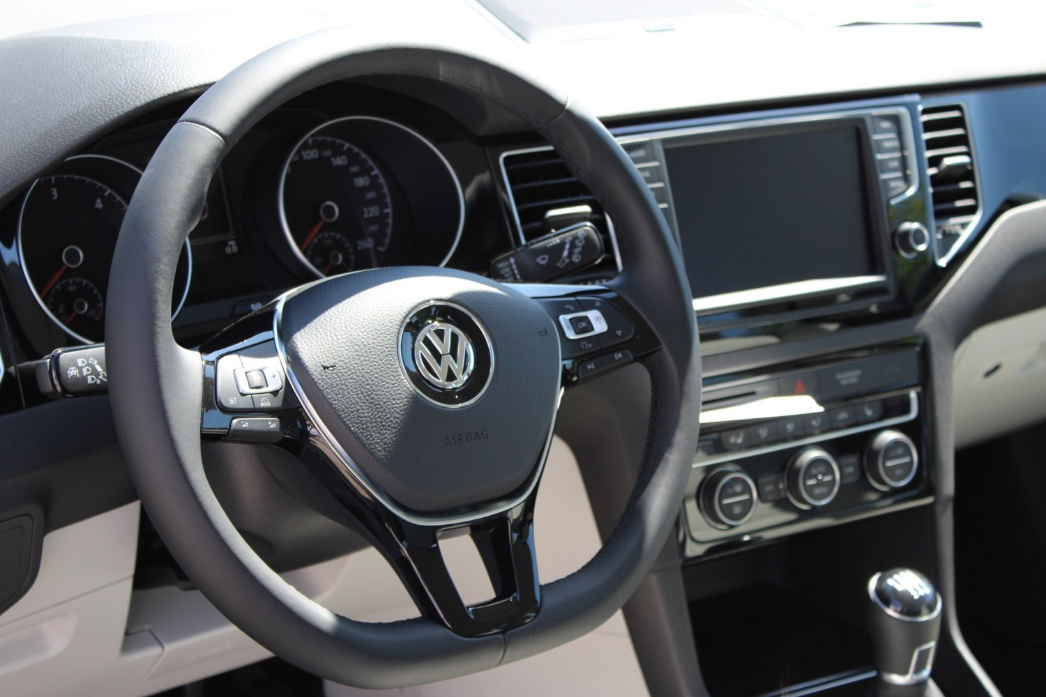 Steering wheel and dashboard with controls and infotainment screen