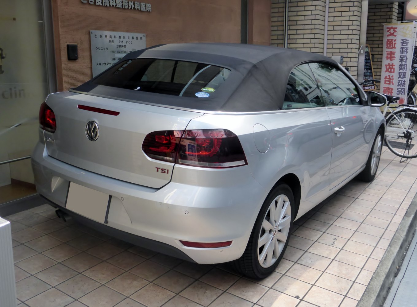 Rear view of a silver convertible with closed soft top and distinctive taillights