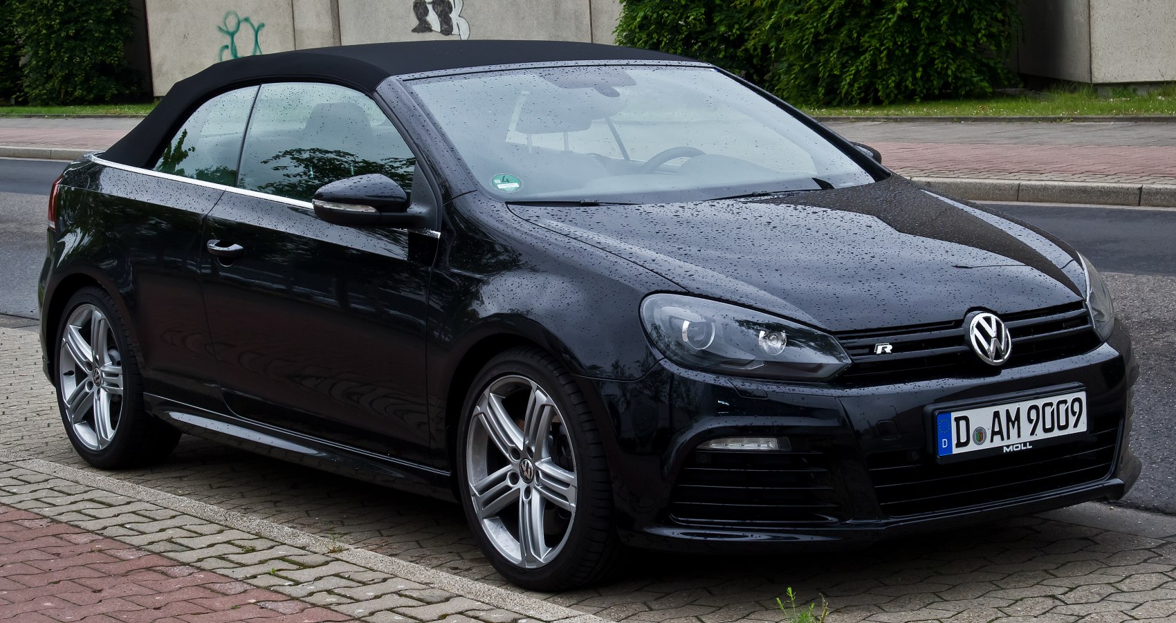 Black convertible with soft top, sporty front, alloy wheels