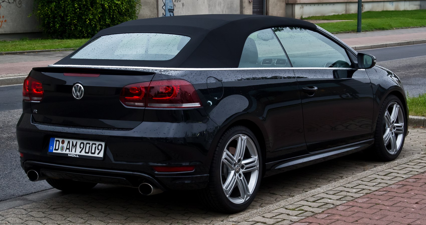 Rear side view of black convertible with soft top and sporty rims
