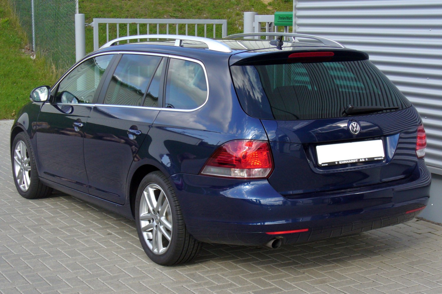 Rear and side view of a dark blue estate vehicle with roof rails and alloy wheels