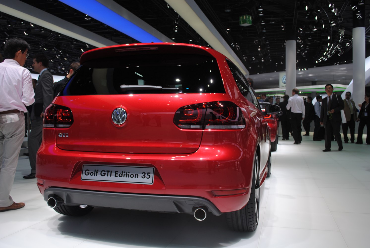 Red hatchback rear with dual exhausts and dark taillights at auto show