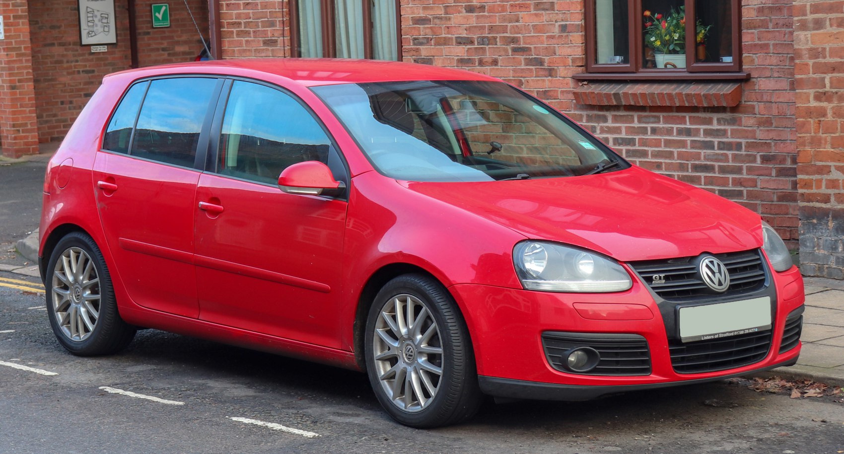 Red 5-door hatchback with alloy wheels, fog lights, and GT badge