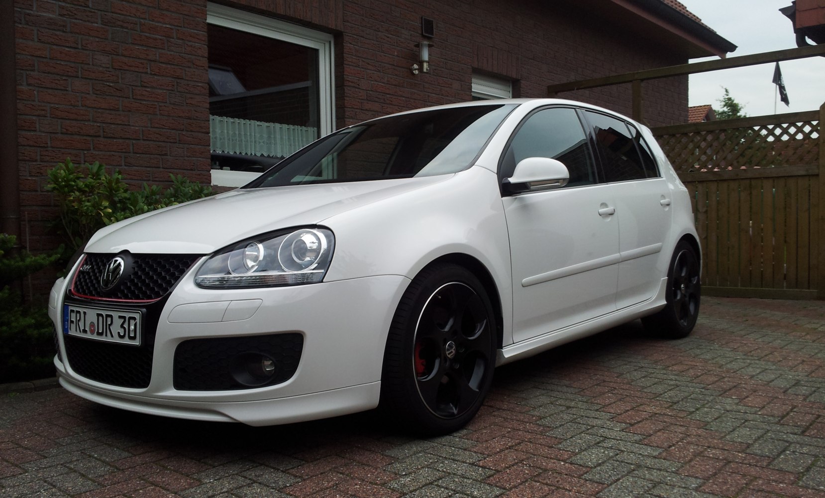 White 5-door hatchback with black alloy wheels and prominent headlights