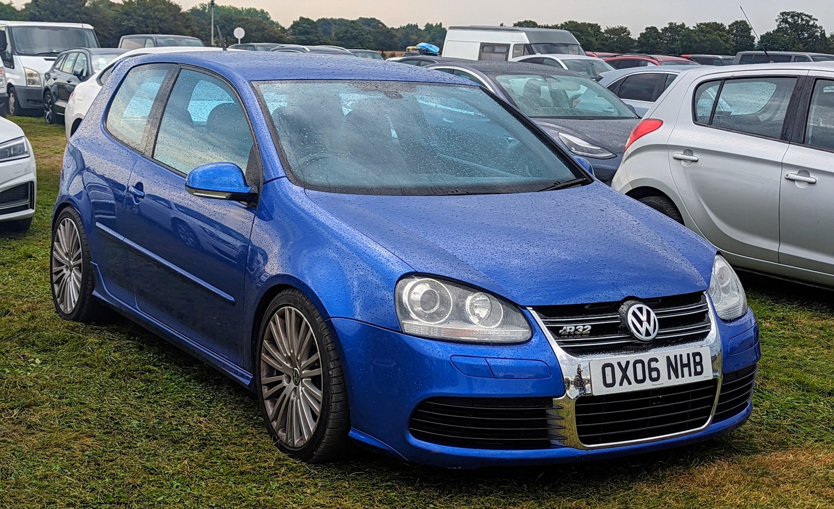 Front view of a blue 3-door hatchback with dual headlamps and R32 badge