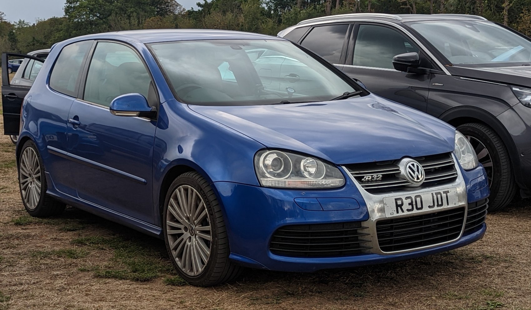 3-door blue hatchback with chrome grille and multi-spoke wheels