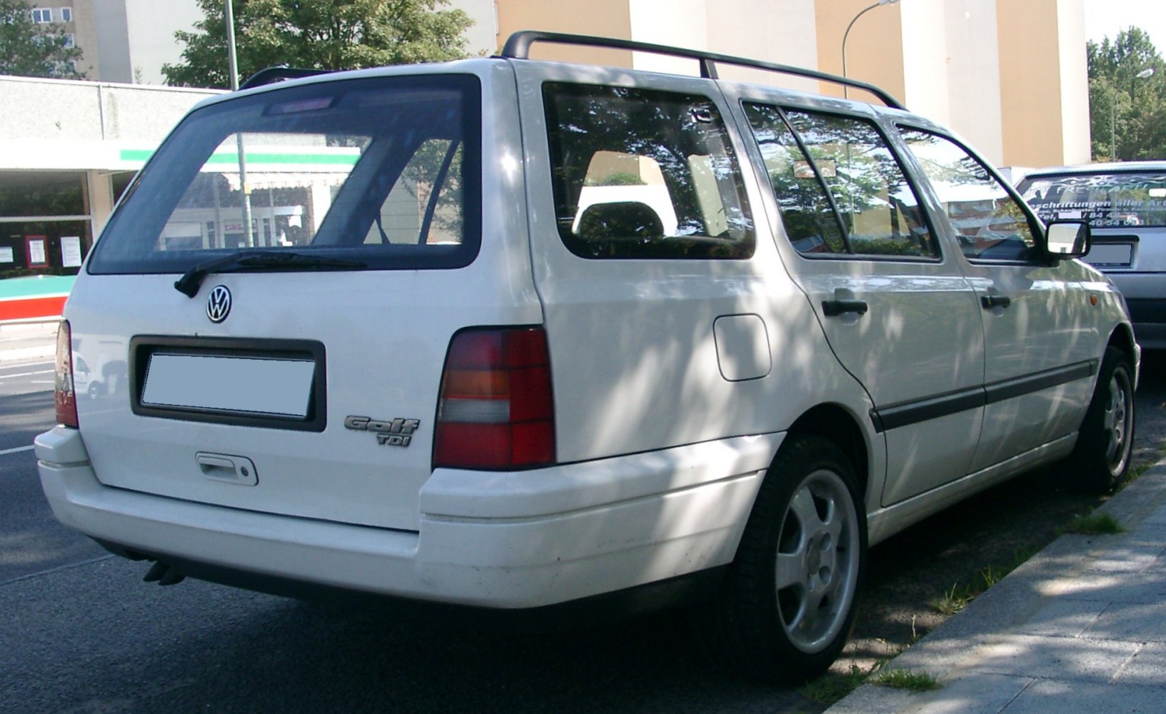 Rear view of a 1990s station wagon with roof rails and distinctive rear window shape