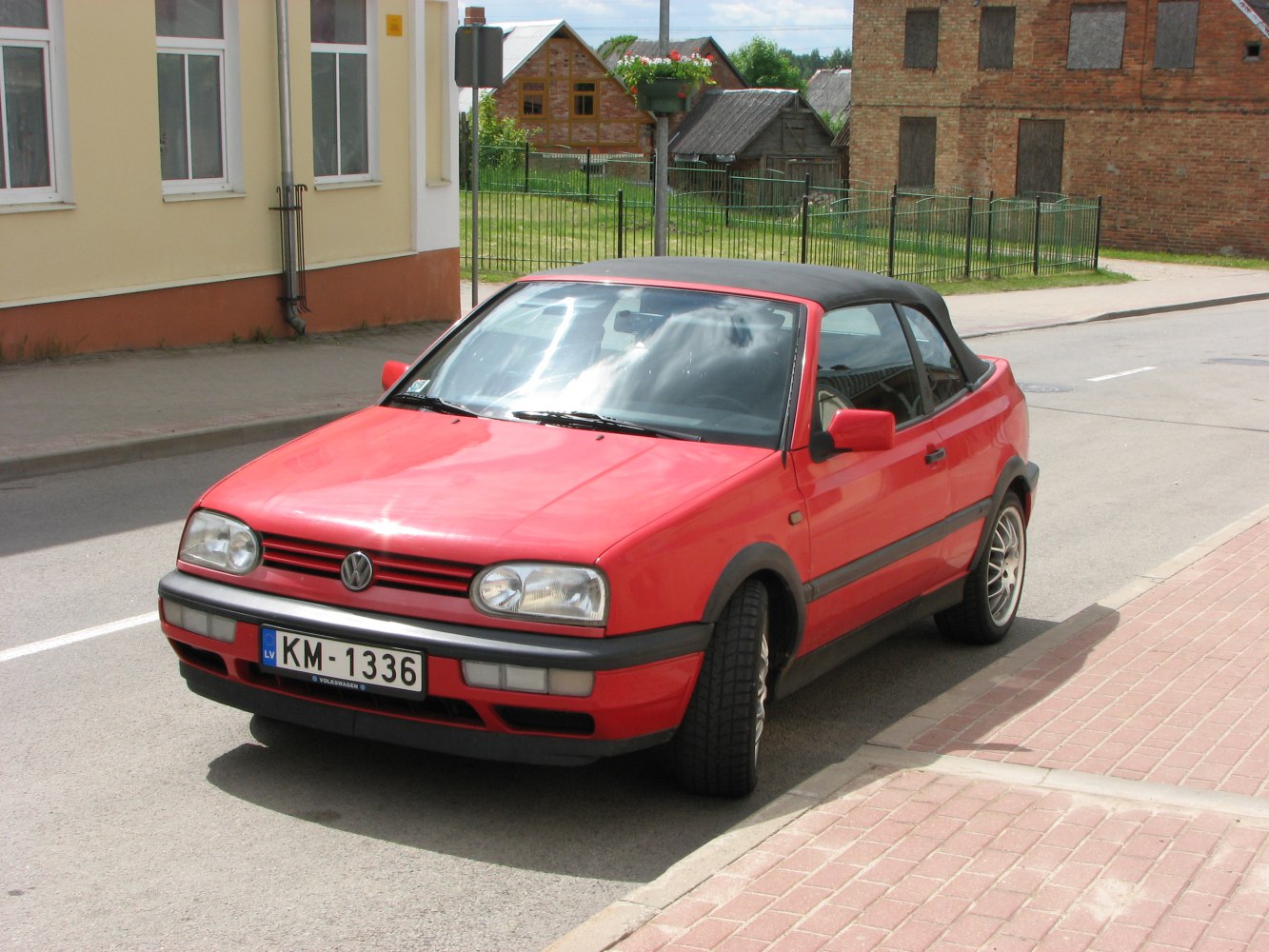 Red convertible with black soft top and alloy wheels parked on street