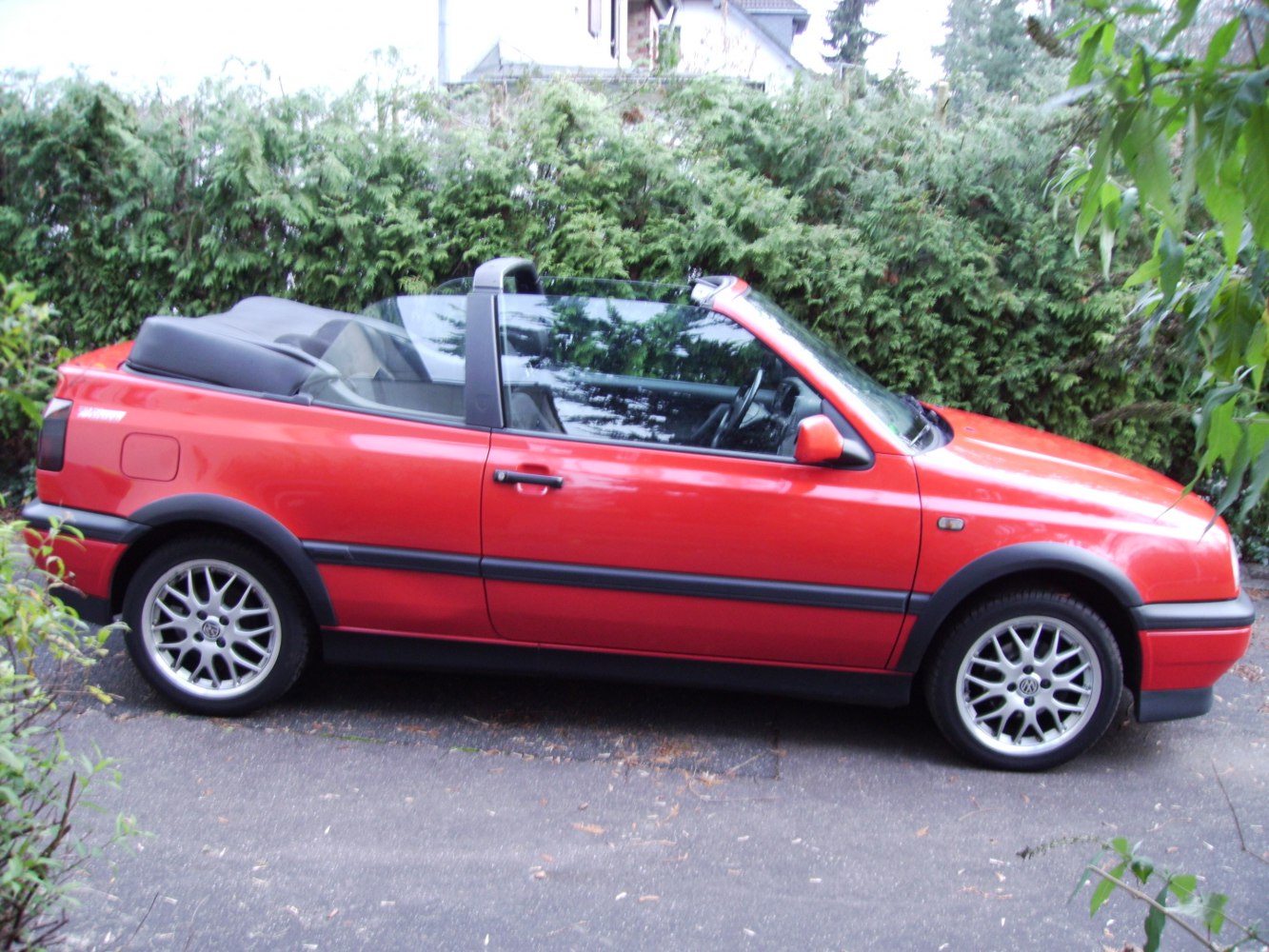 Red convertible with black folded roof and alloy wheels