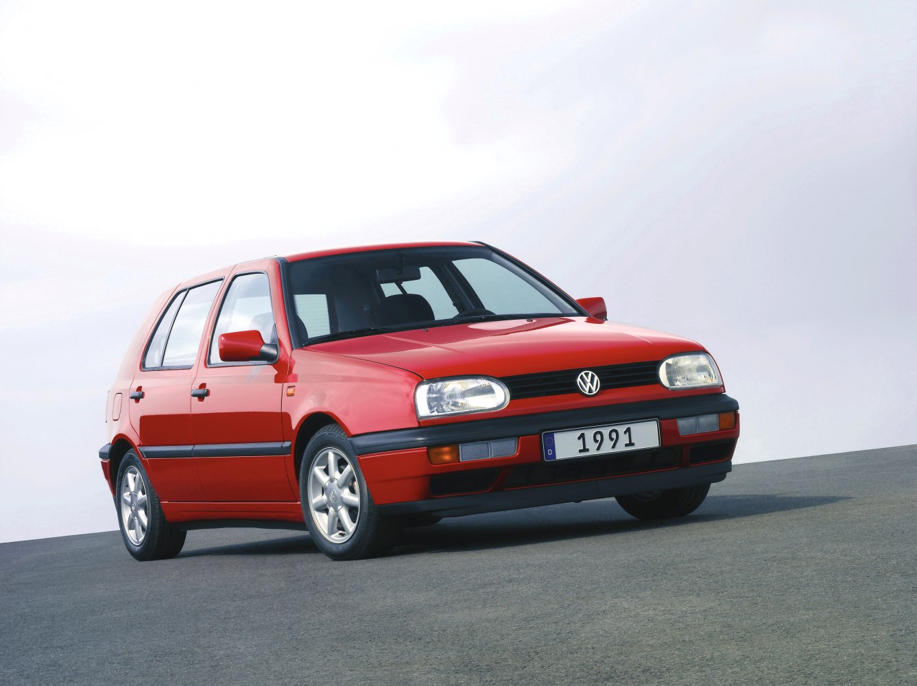 Front-side view of a red hatchback with distinctive rounded headlights.