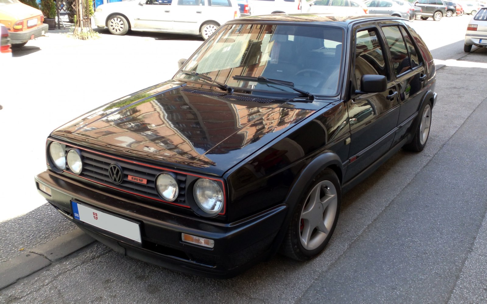 Black Volkswagen Golf II 5-door hatchback with quad headlights and 5-spoke alloy wheels