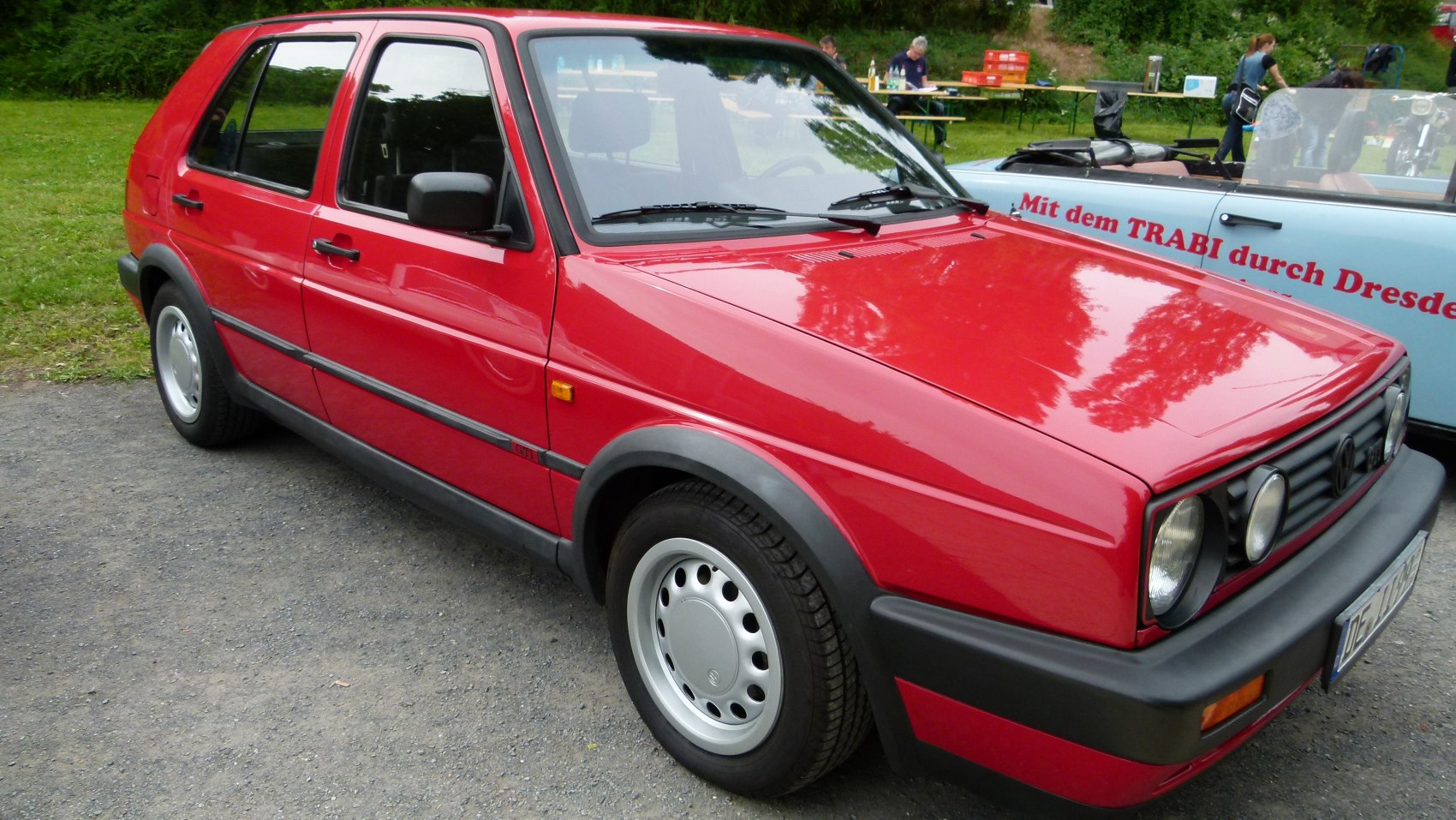 Red 5-door facelifted vintage hatchback with black trim and round headlights