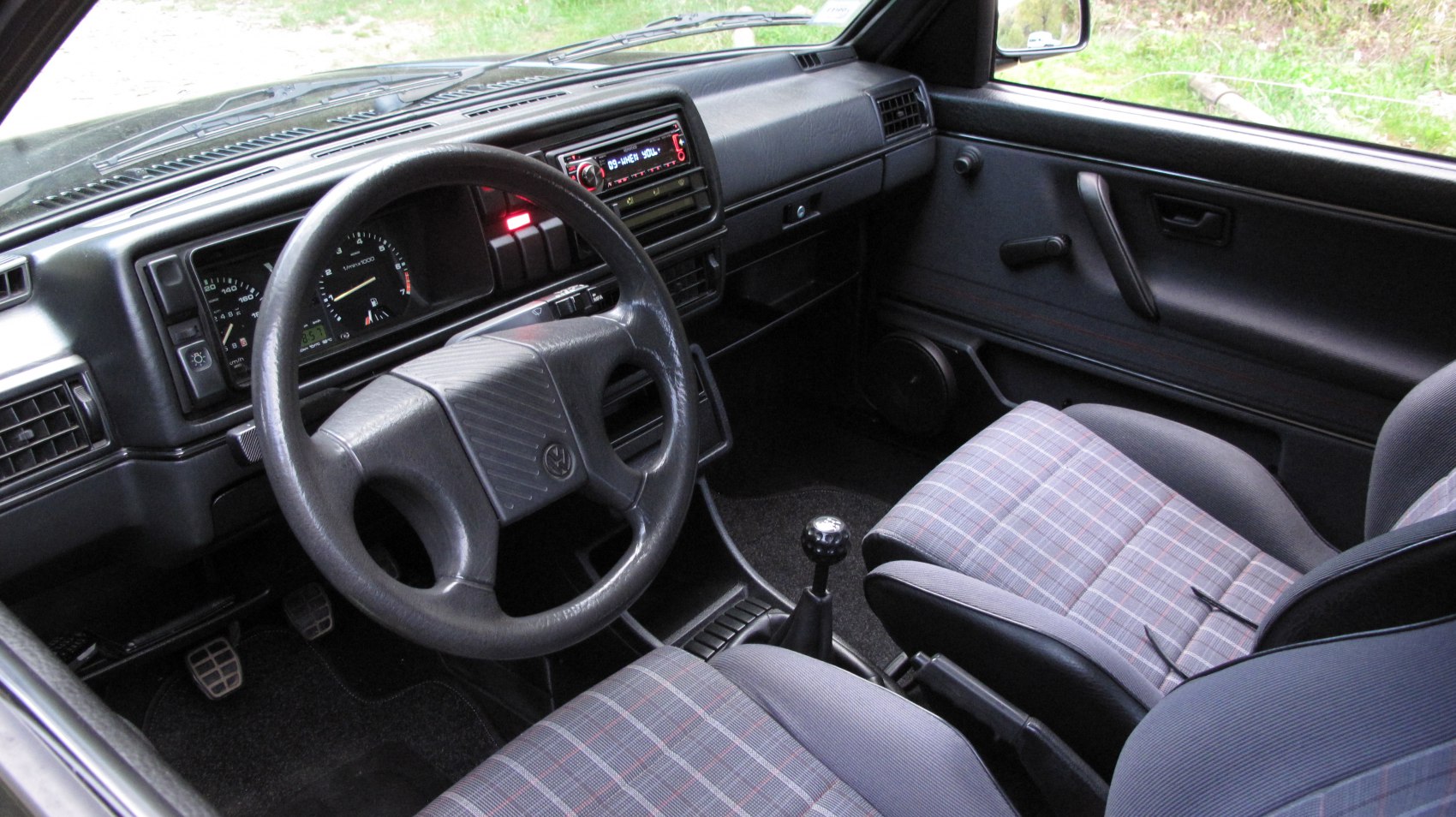 Dashboard, steering wheel, plaid cloth seats, manual gear knob