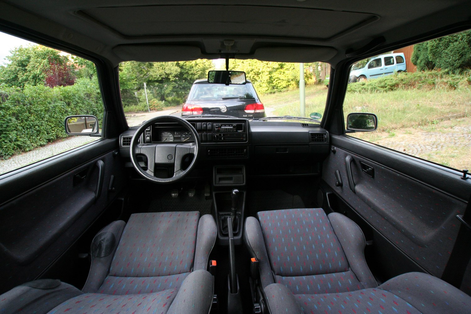 Steering wheel, dashboard, manual gear shift, and patterned front seats