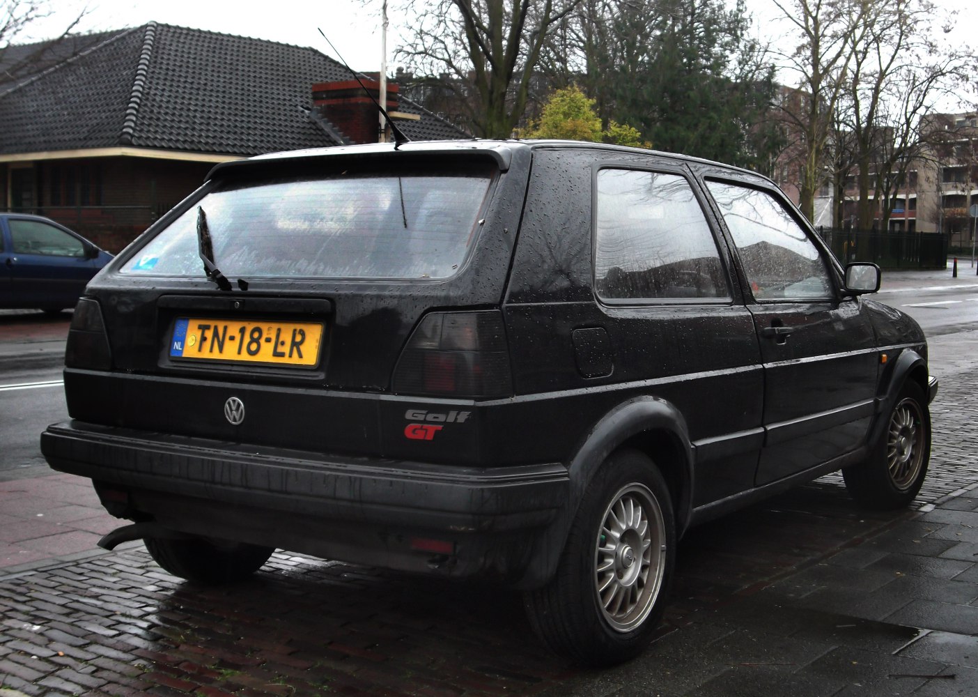 Rear view of 3-door hatchback with smoked tail lights on wet pavement