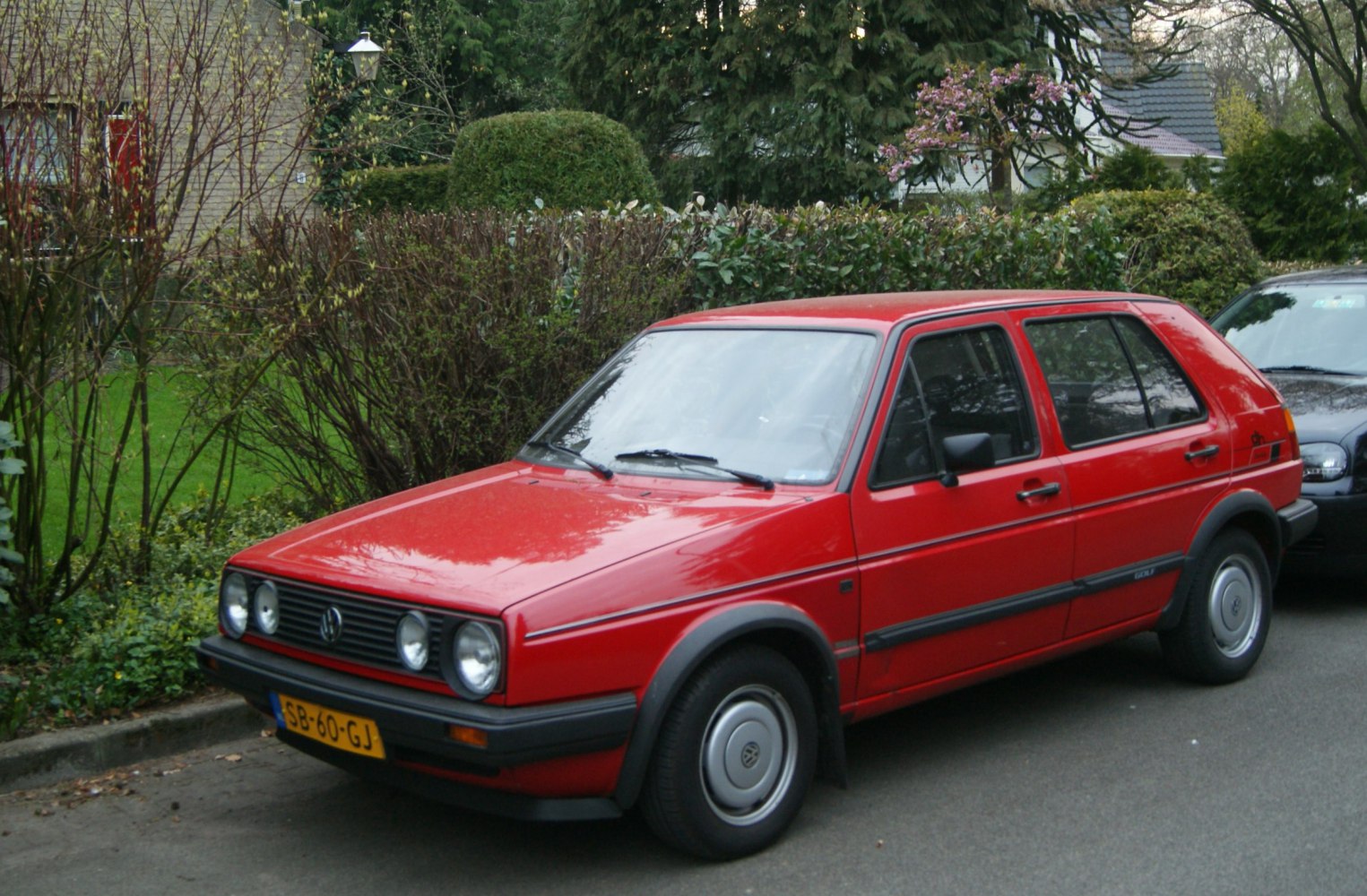 Red 5-door hatchback with quad circular headlights and black trim