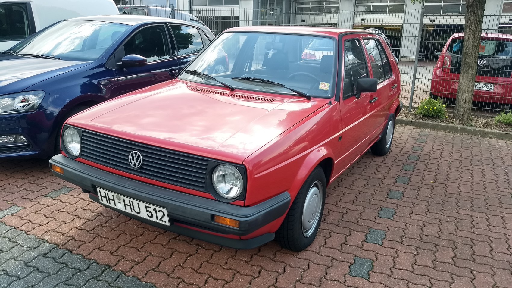 Red 5-door hatchback with classic front grille and round headlights