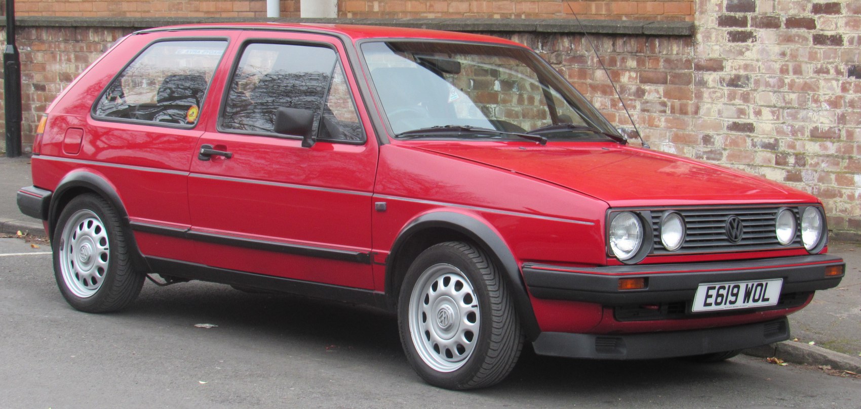 Red 3-door hatchback with dual round headlights and black trim