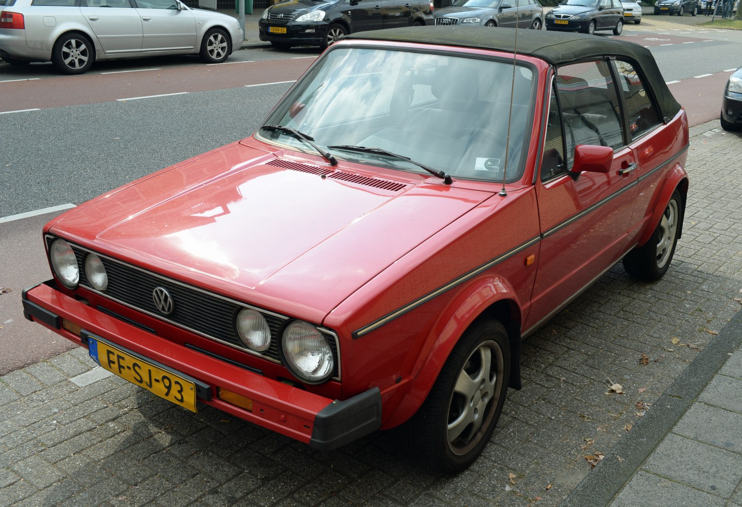 Red convertible with quad round headlights and black soft top roof