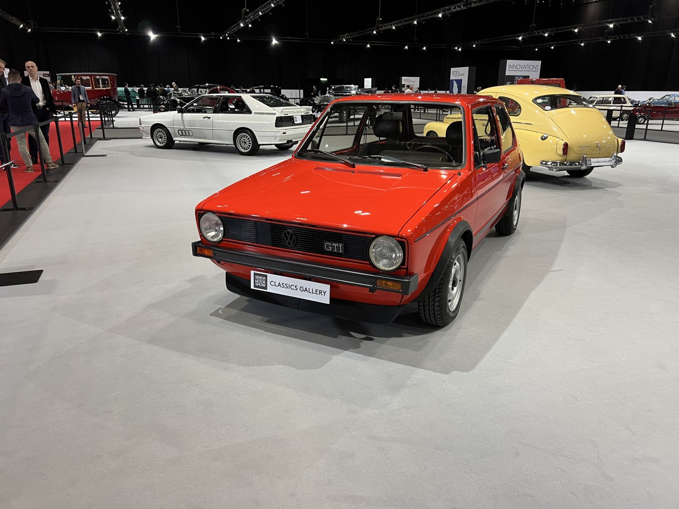 Front view of a red 3-door hatchback with round headlights and black grille