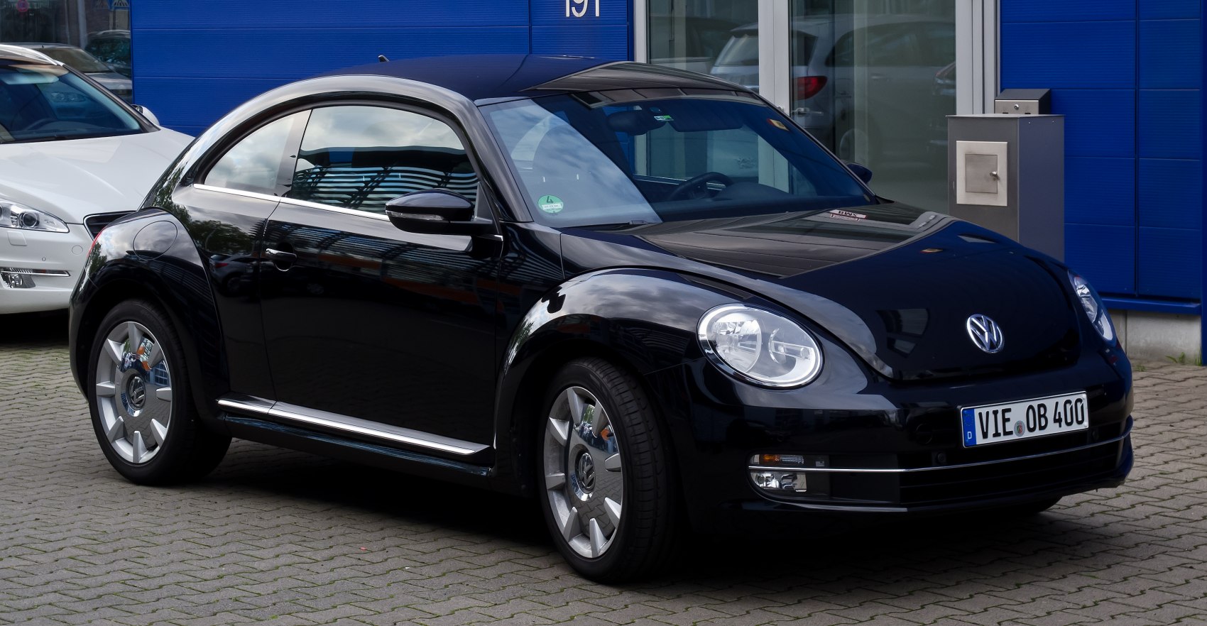 Sleek black compact rounded coupe with distinctive headlights and reflective finish.