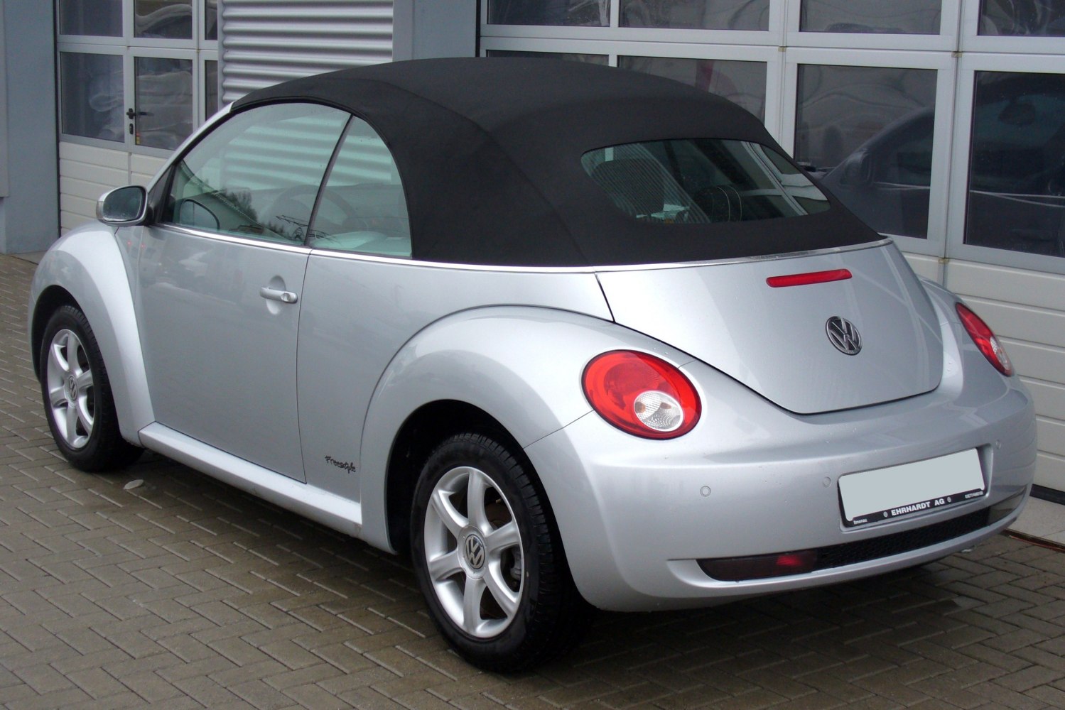 Silver convertible with black soft top and rounded tail lights