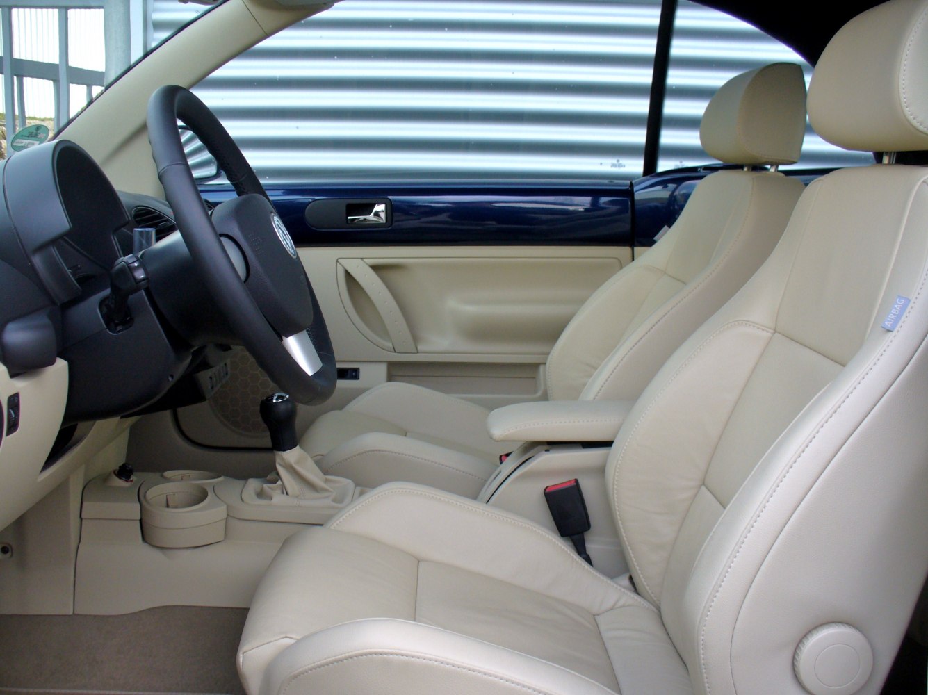 Beige leather front seats and black steering wheel with manual gear shift