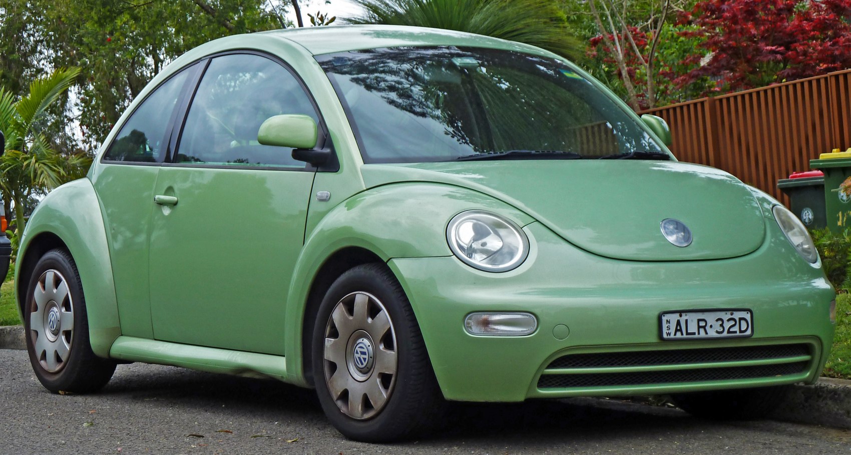 Green compact car with rounded headlights and curved retro design.