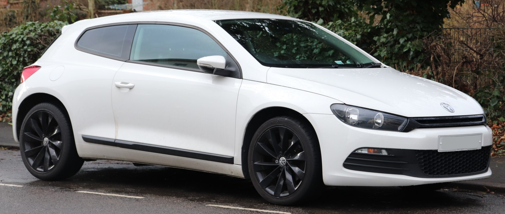 White hatchback with black alloy wheels and tinted windows.