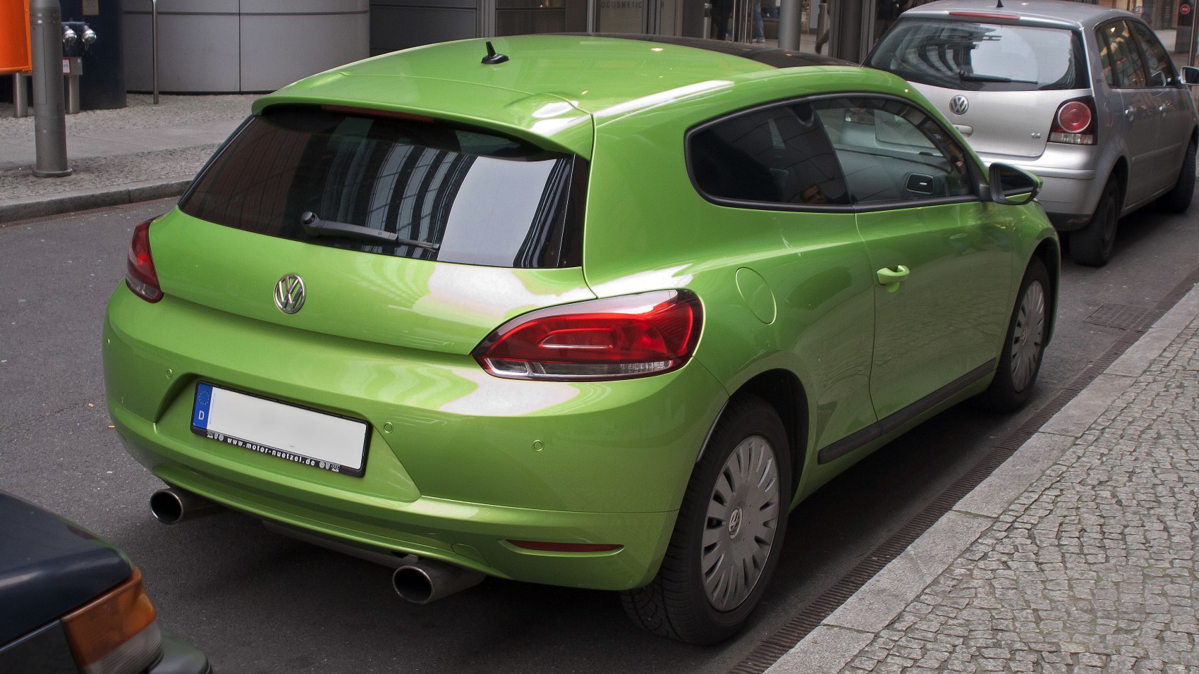 Rear view of green hatchback with dual exhaust and tinted rear windows