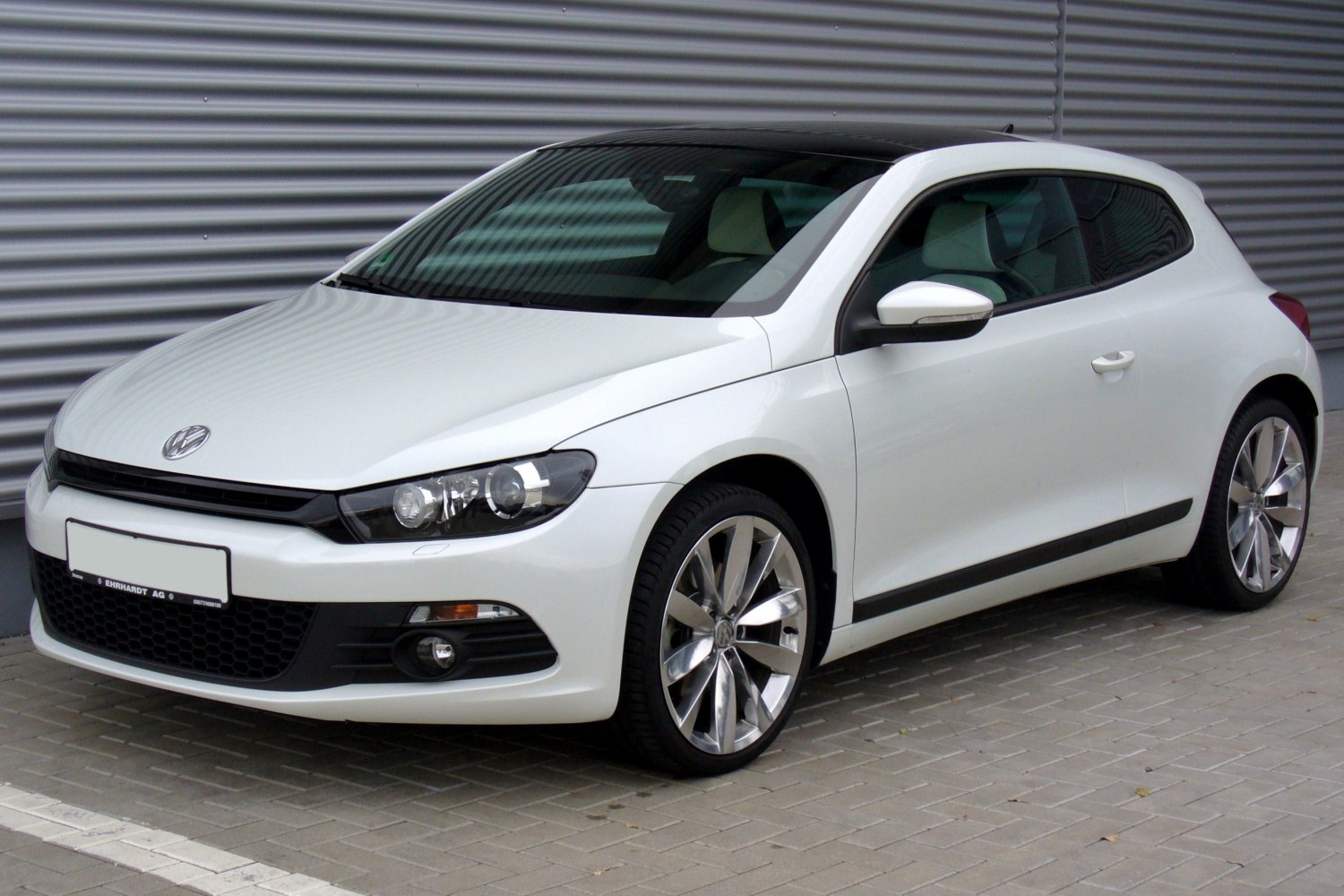 White sporty hatchback with sleek headlights and alloy wheels