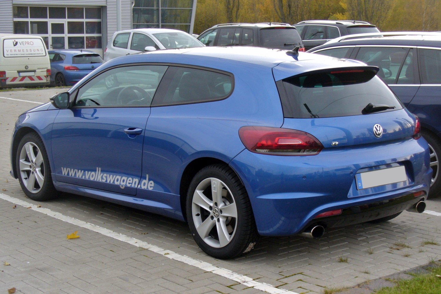 Blue hatchback with rear-side angle, distinctive taillights, and dual exhaust