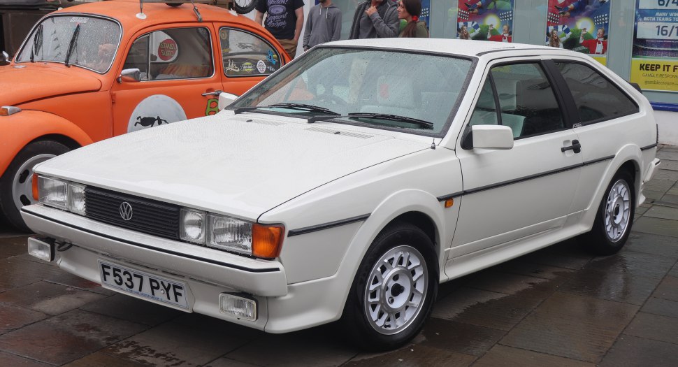 White two-door sports coupe with rectangular headlights and alloy wheels