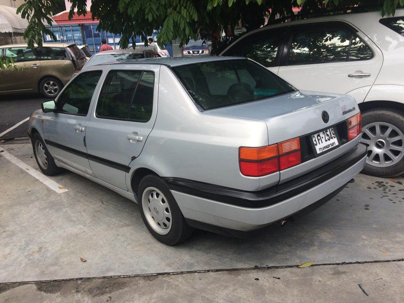 Rear and side view of a classic silver sedan with distinct tail lights and simple trim.