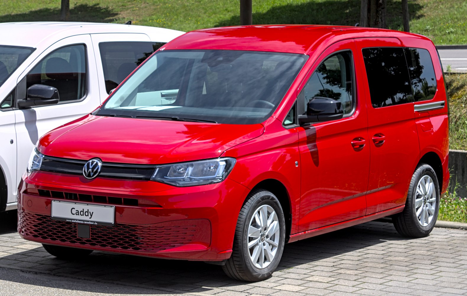 Front view of red compact van with sleek headlights and honeycomb grille