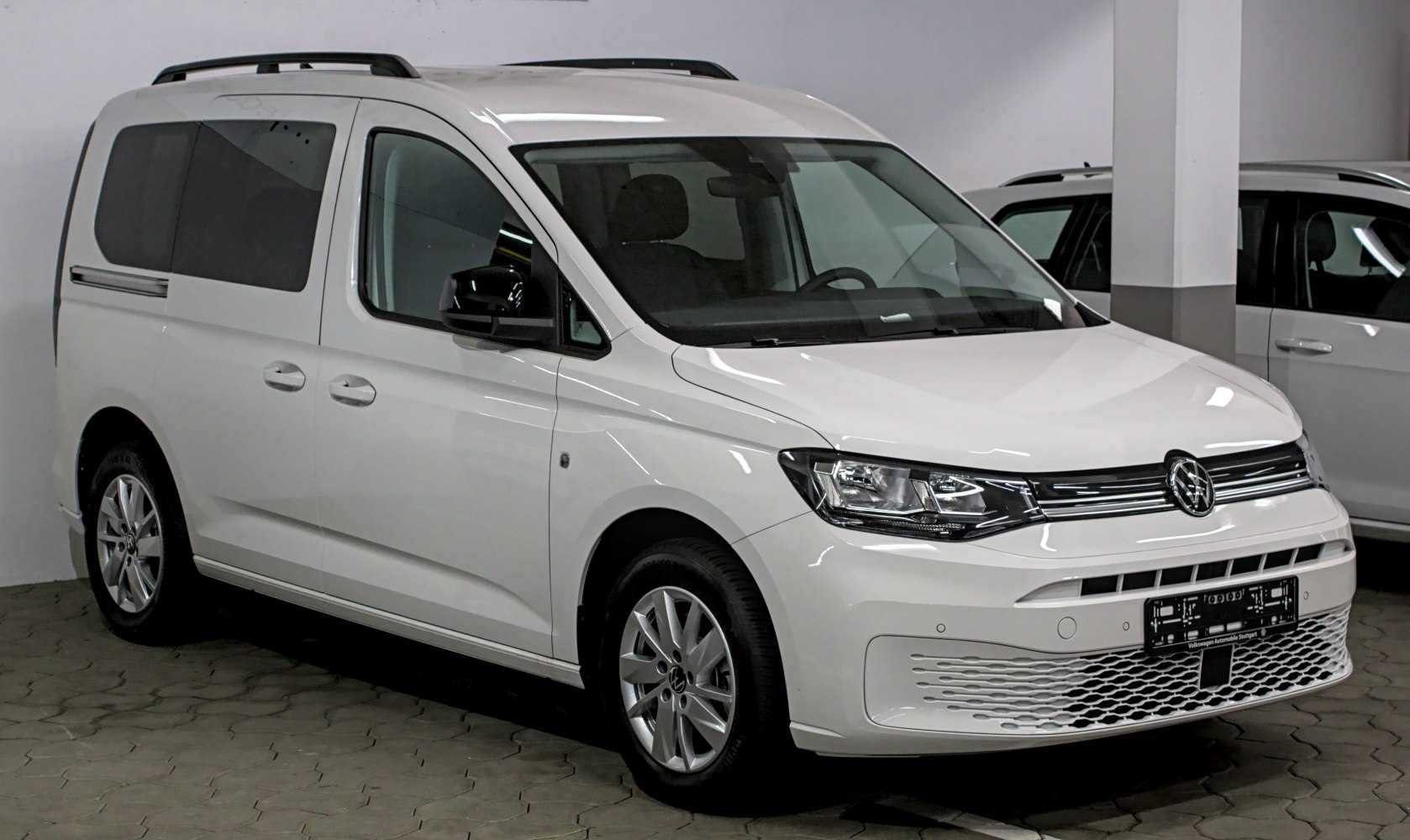 Front and side view of mid-sized van with roof rails and alloy wheels