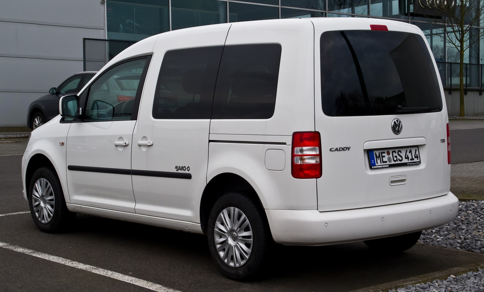 Rear-side view of a white panel van with tinted windows and rear hatch