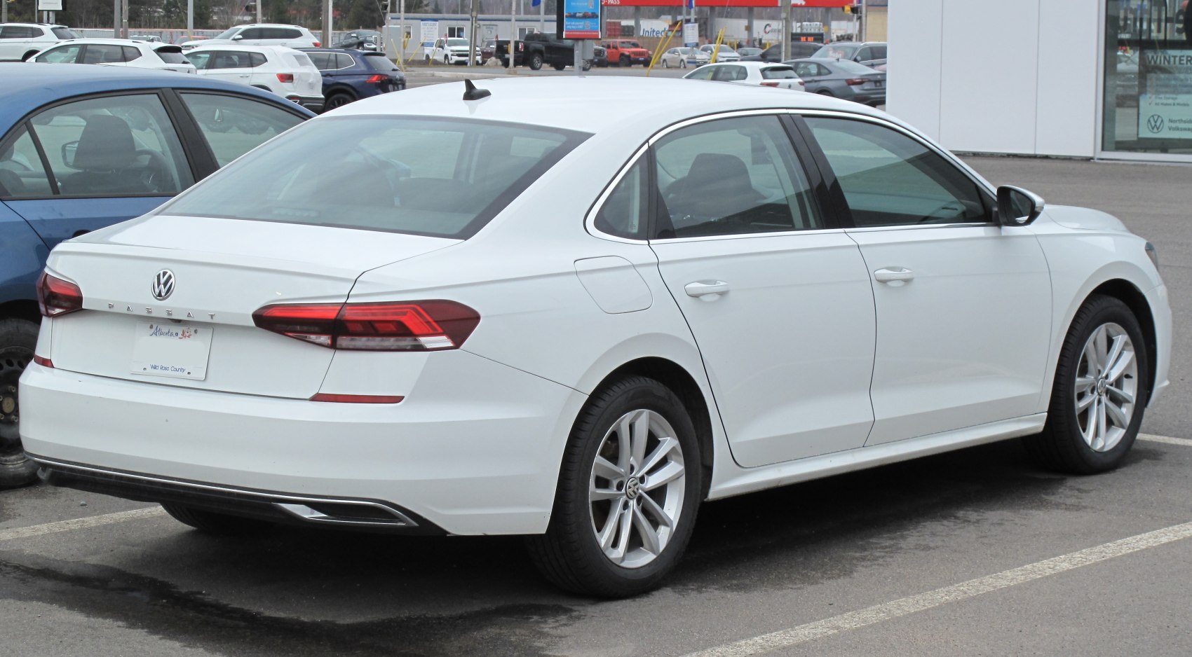 Rear and side view of a white sedan with alloy wheels and taillights