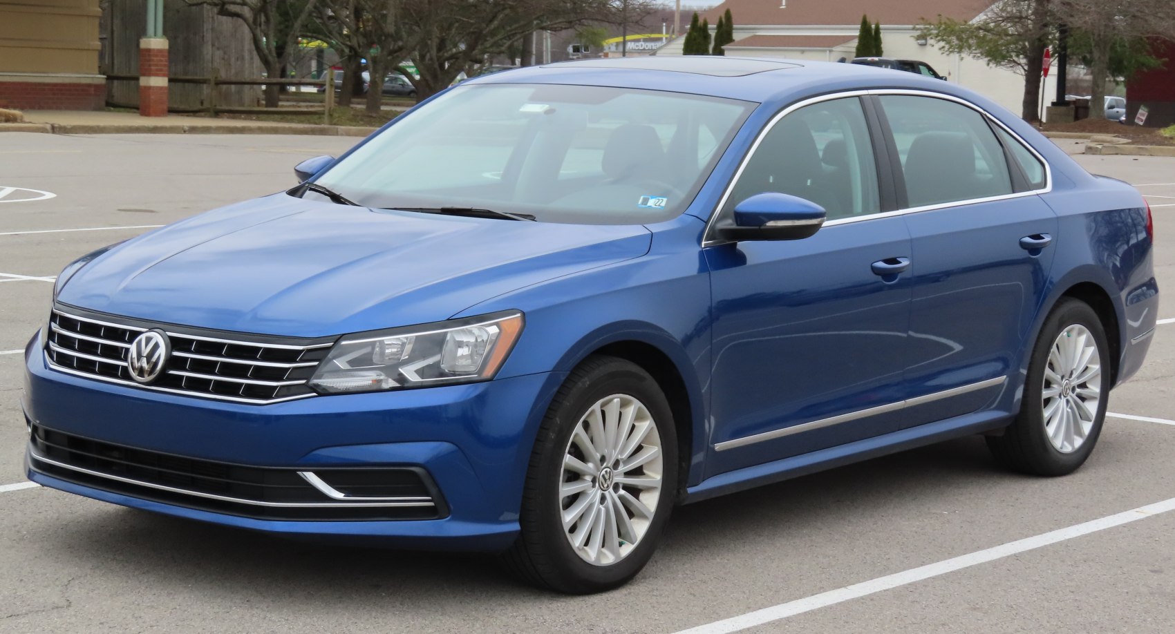 Front side view of a blue mid-size sedan with LED headlights and alloy wheels