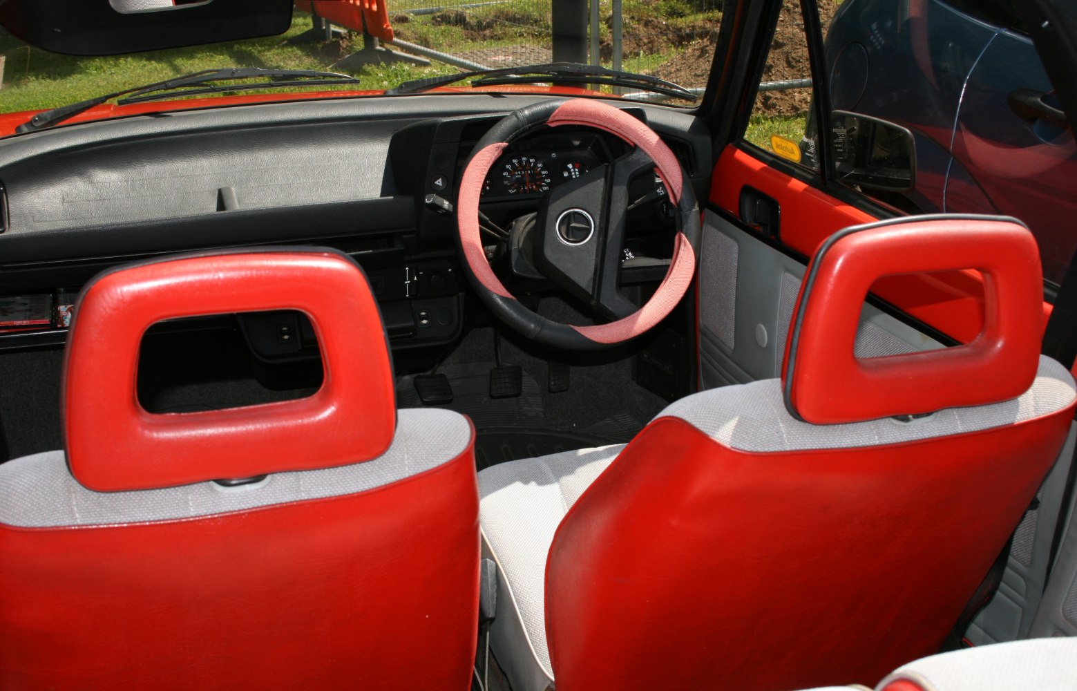 Red-trimmed steering wheel and retro car seats in vintage interior